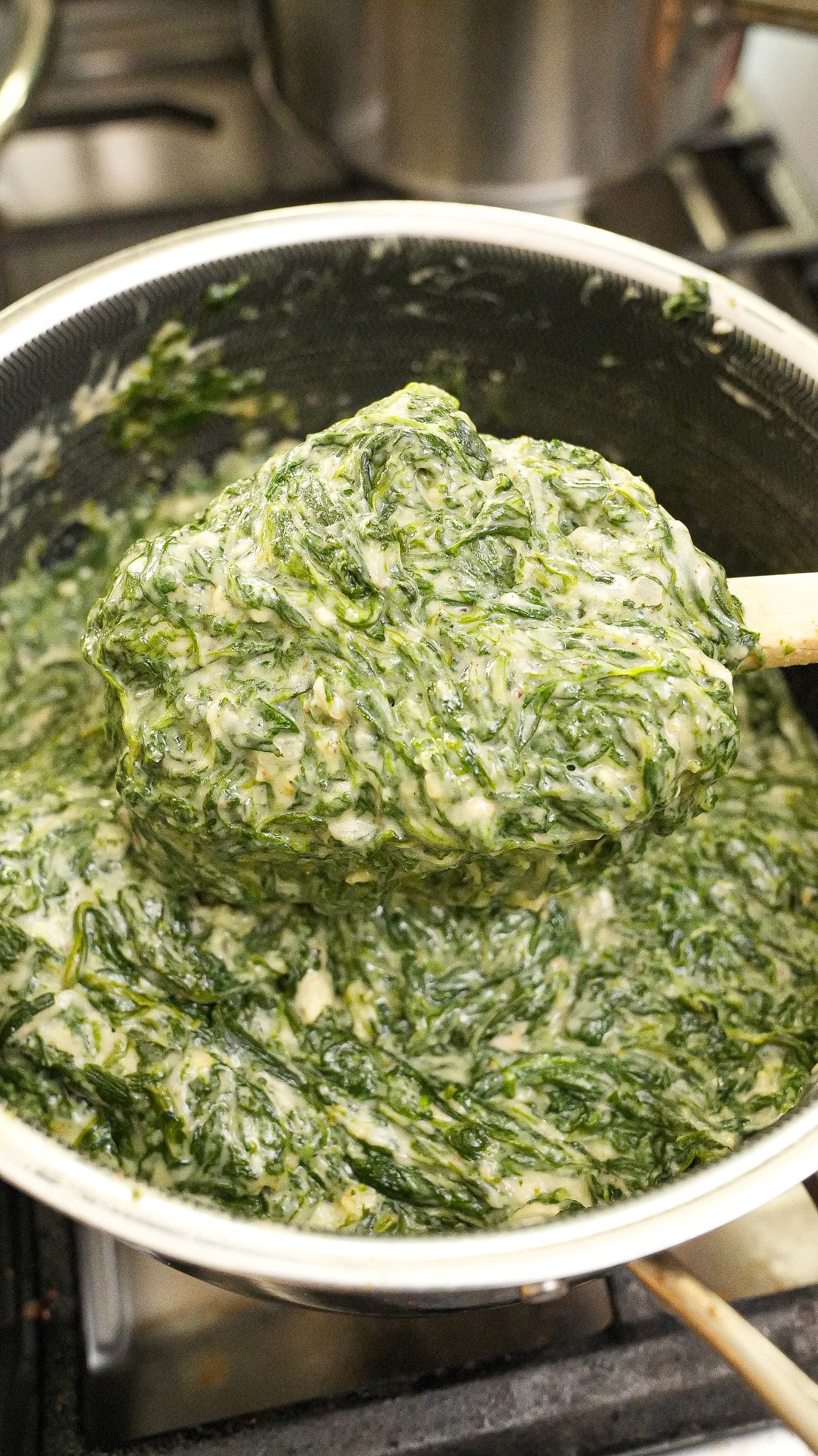 Creamed spinach cooked in a pot with a spatula.