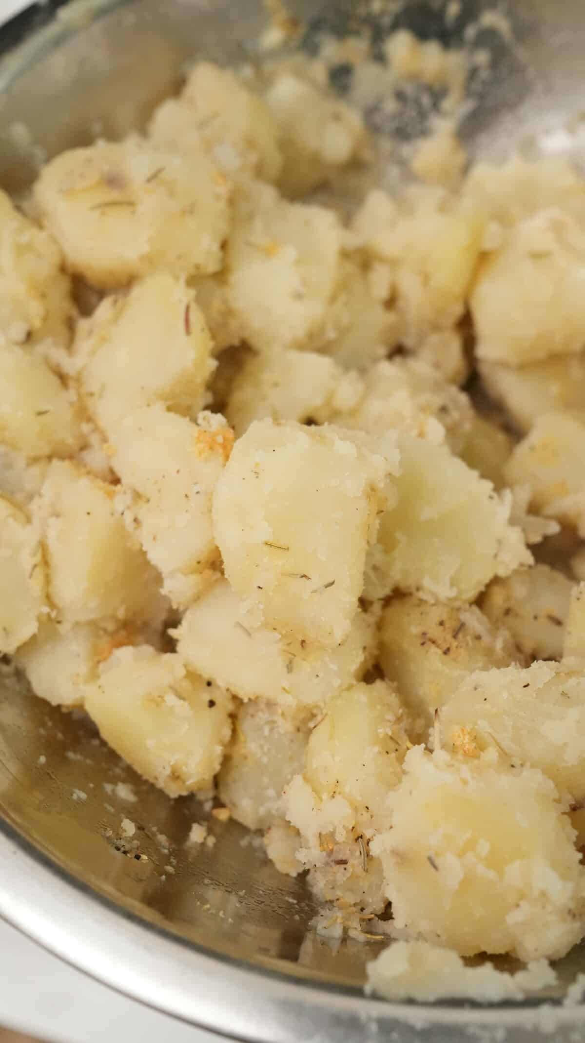 Seasoned potatoes in a bowl that are roughed around the edges.