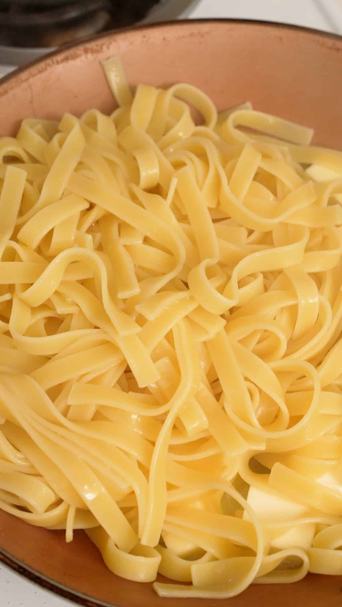 Fettucine added to a pan with butter.