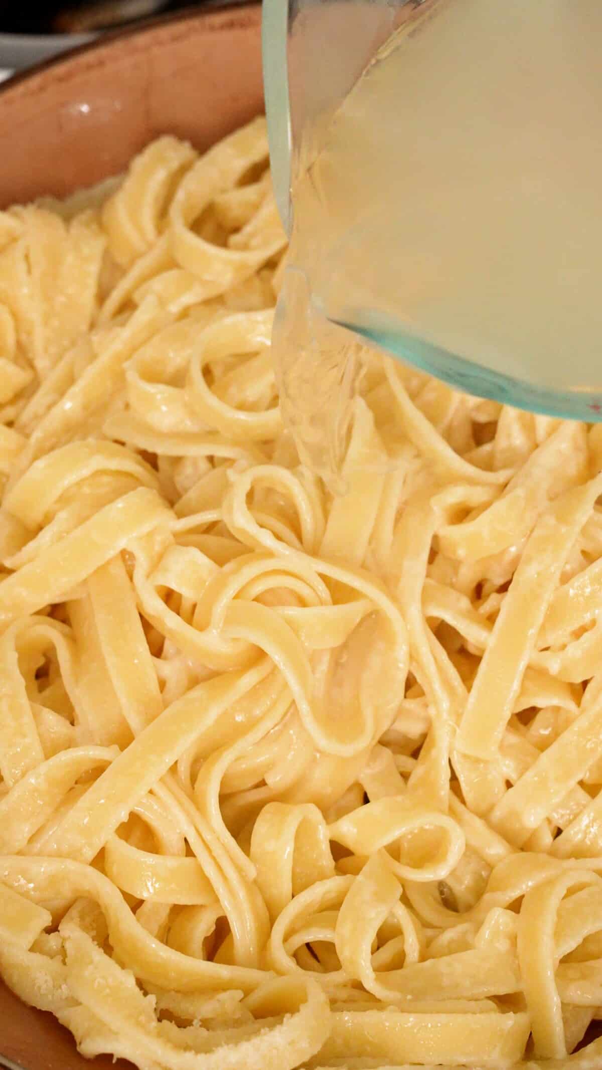 Pasta water being added to the pasta, cheese, and butter in a pan.