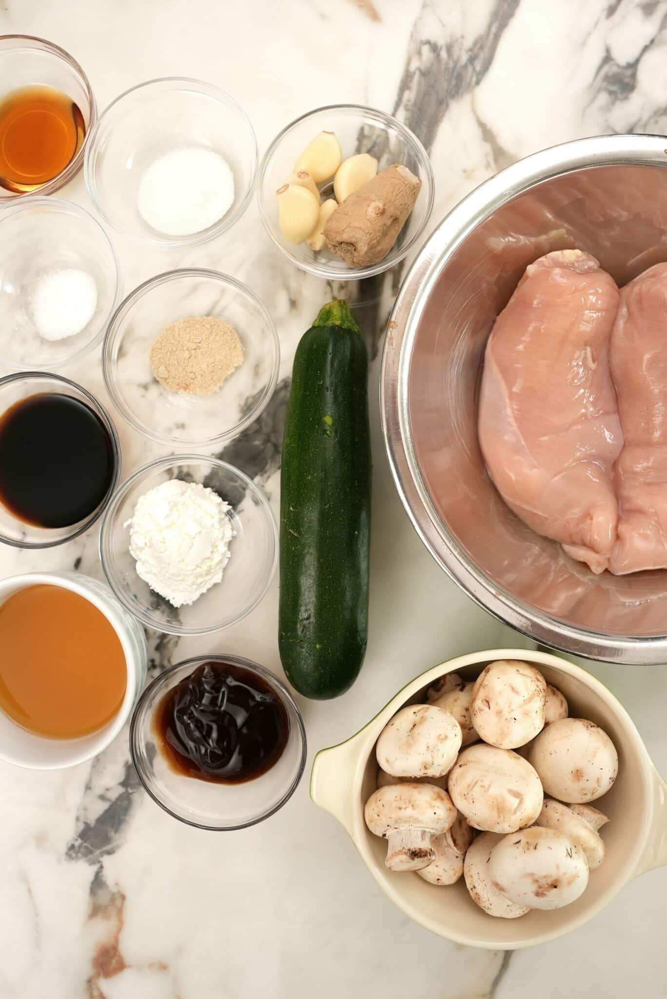 Raw ingredients for Mushroom Chicken on a table in bowls.