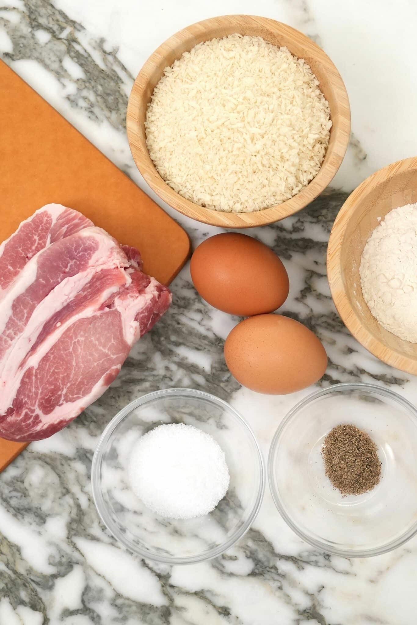 Raw ingredients for pork katsu on a table.