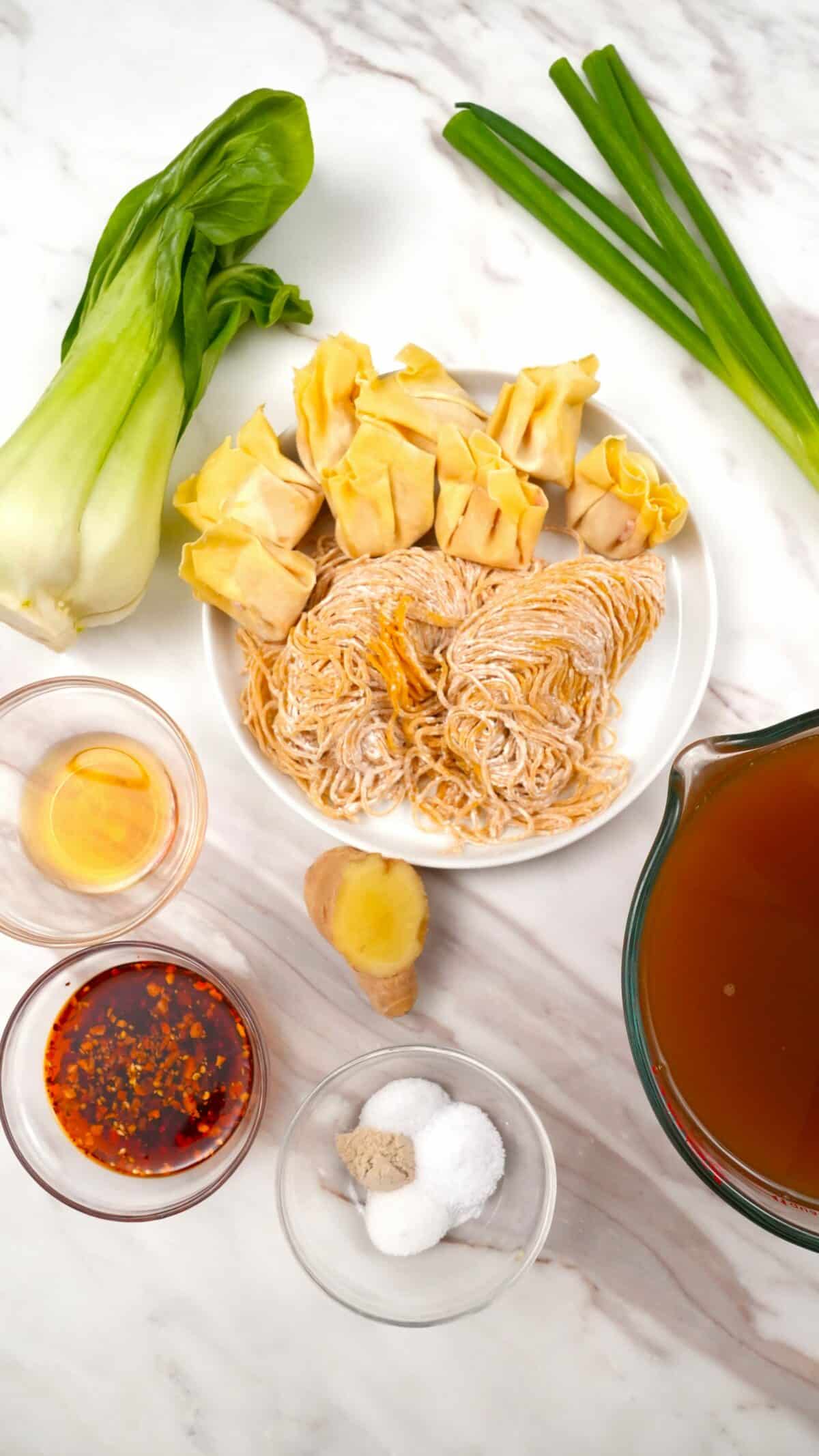 Raw ingredients for wonton noodle soup in bowls.