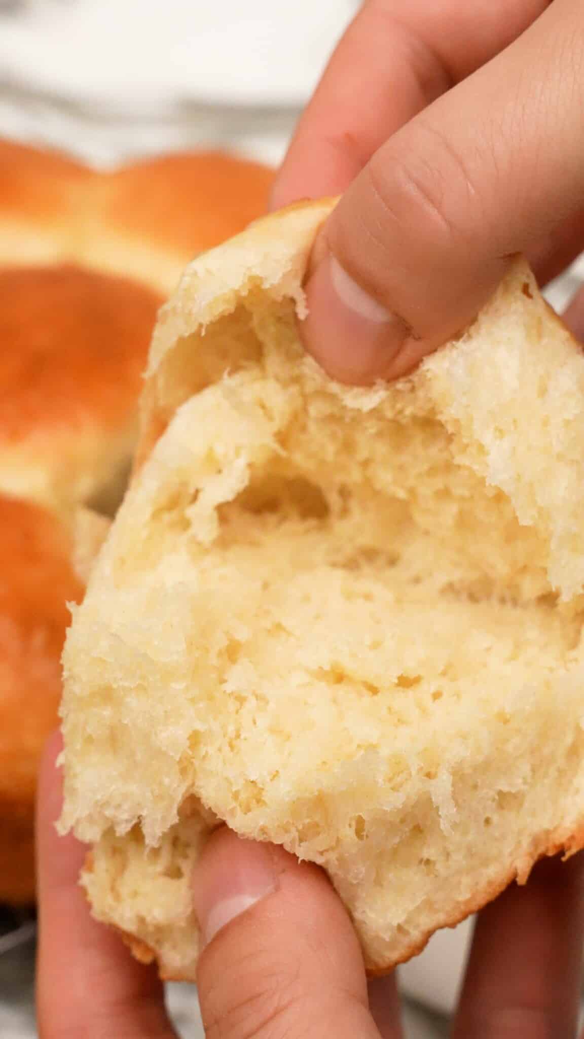 Milk bread roll being pulled open with hands.