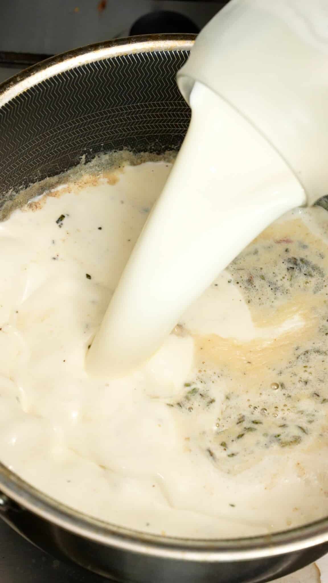 Milk and heavy cream being added to the roux in a pot.