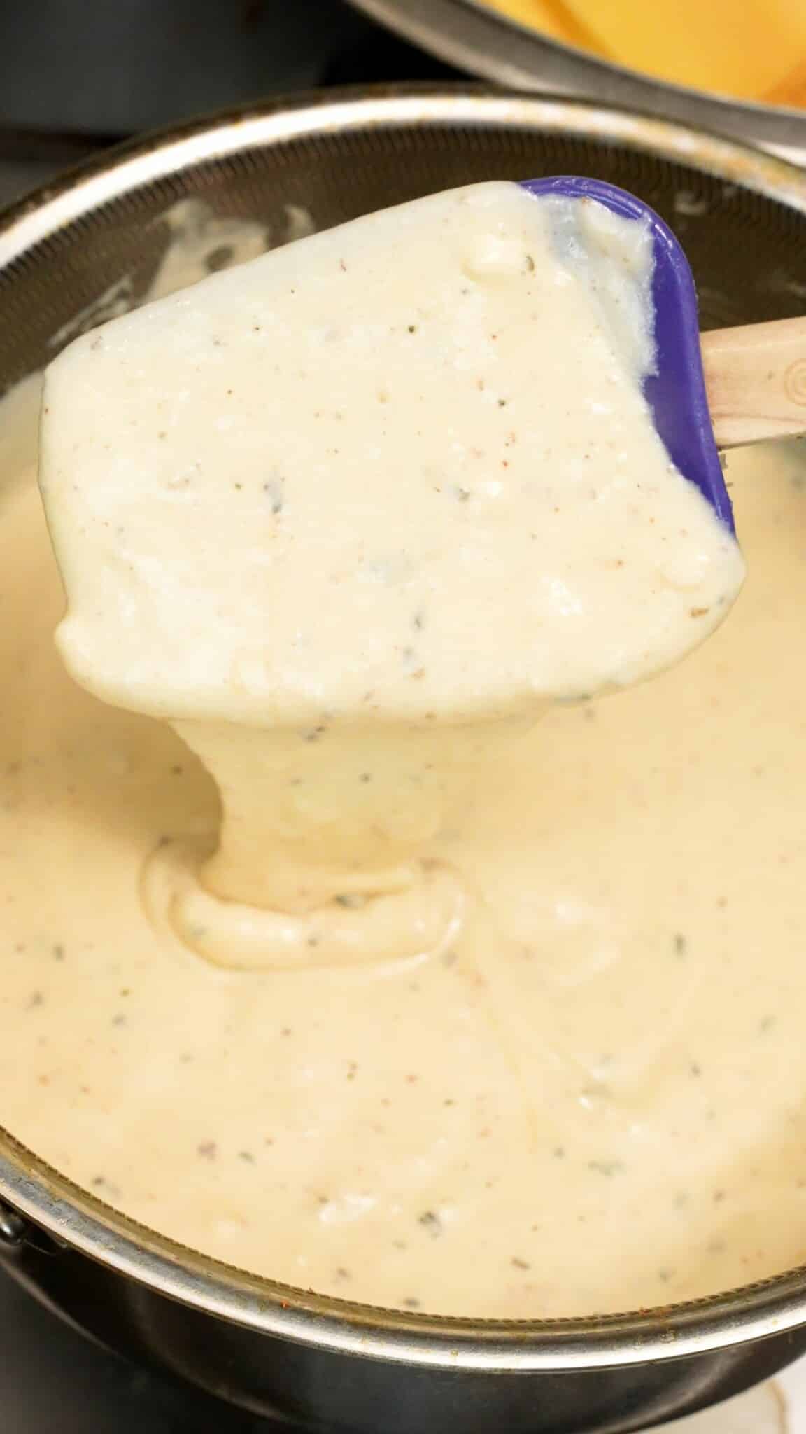 A spatula mixing the bechemel sauce.