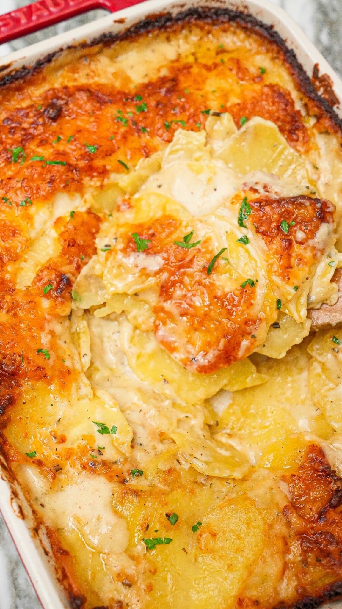 Cheesy Potatoes au Gratin in a baking dish with a spatula.