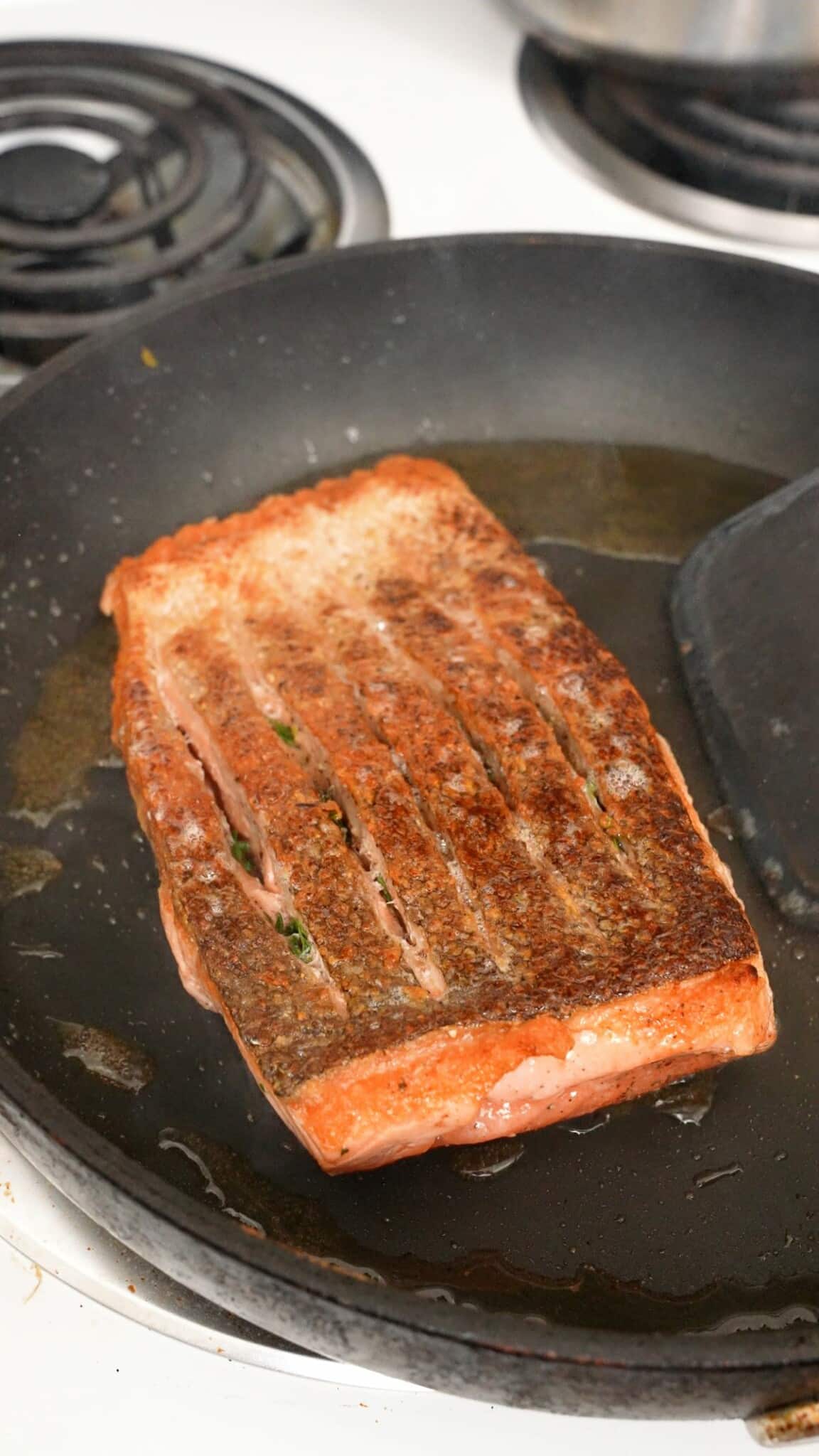 A salmon filet flipped in a pan.