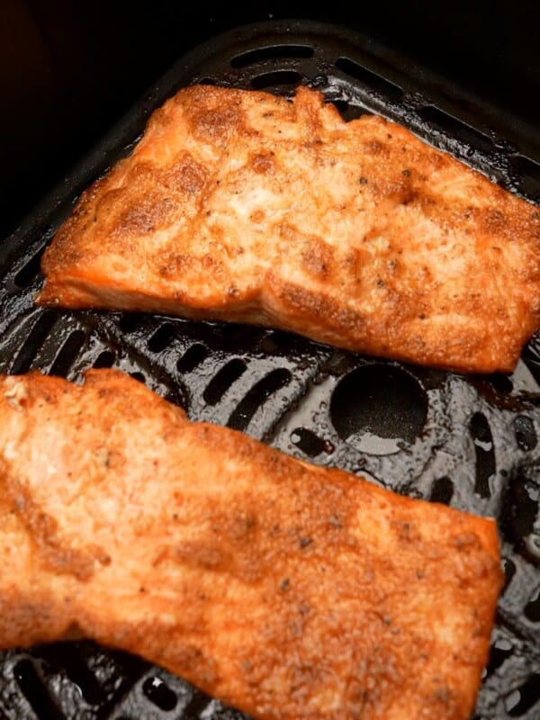 Two filets of cooked salmon in the air fryer.