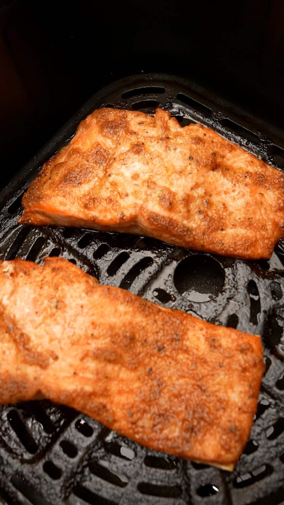 Two filets of cooked salmon in the air fryer.