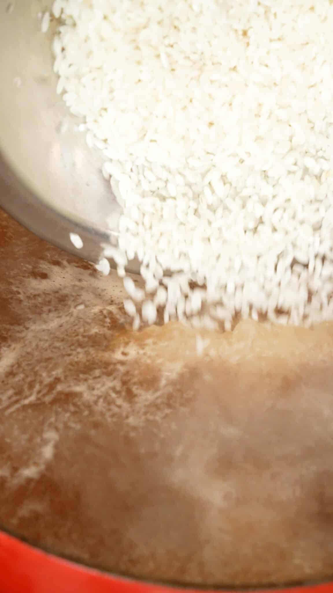 Washed white rice being added to broth in a pot for Congee.