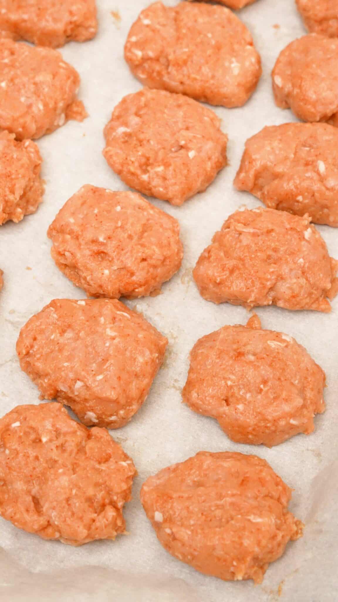 Raw chicken nuggets shaped on a tray prepped for the air fryer.