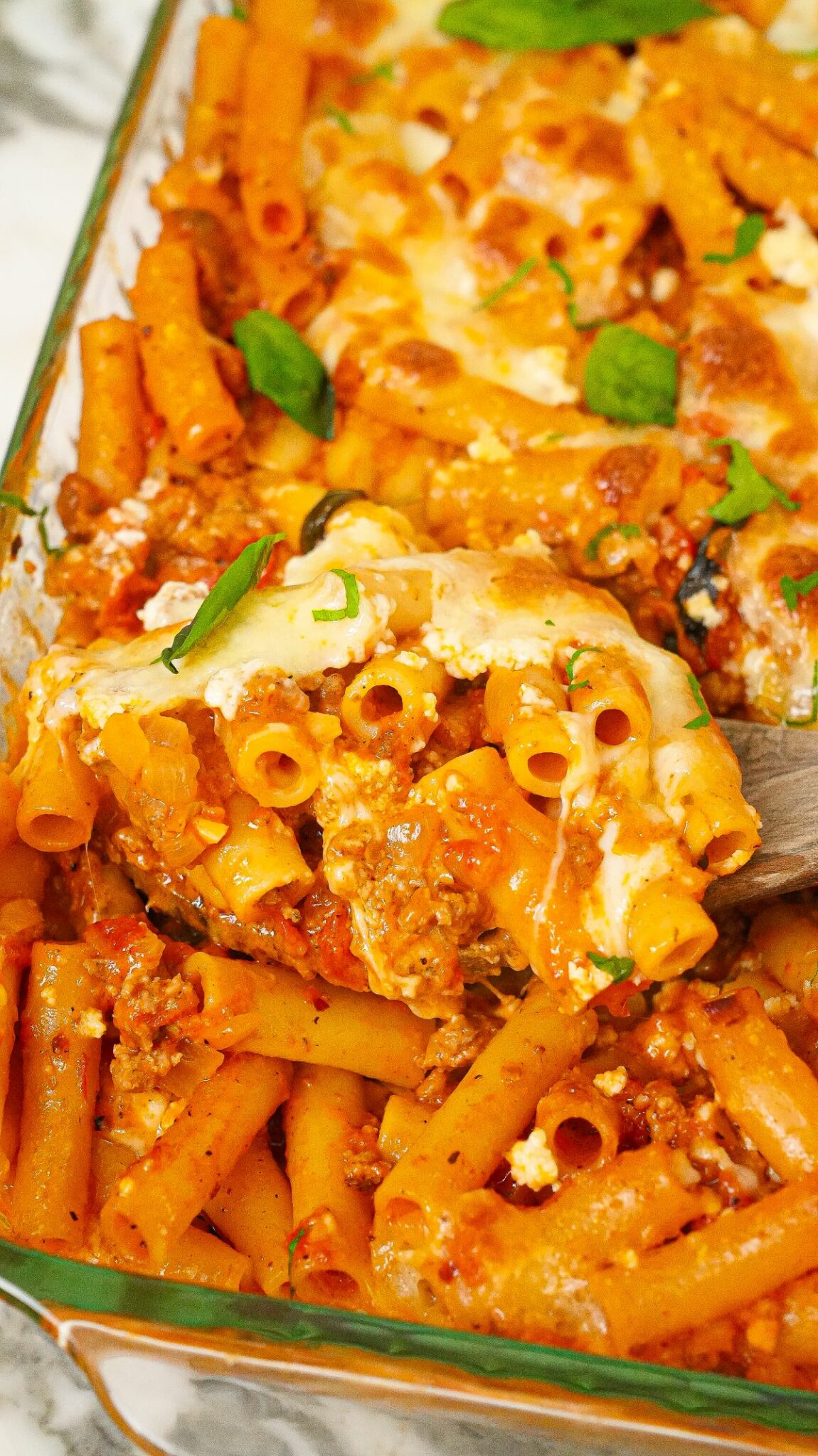 A spatula lifting up a serving of Baked Ziti from the baking dish.