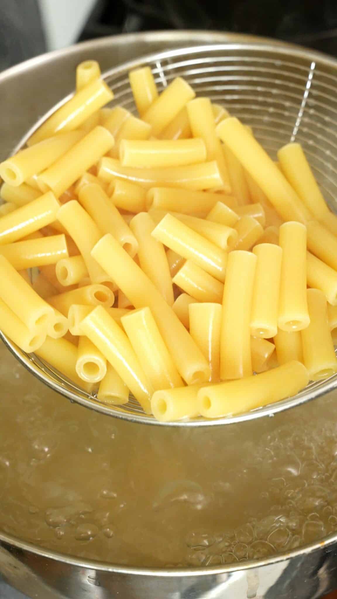 Ziti noodles being drained from cooking water.