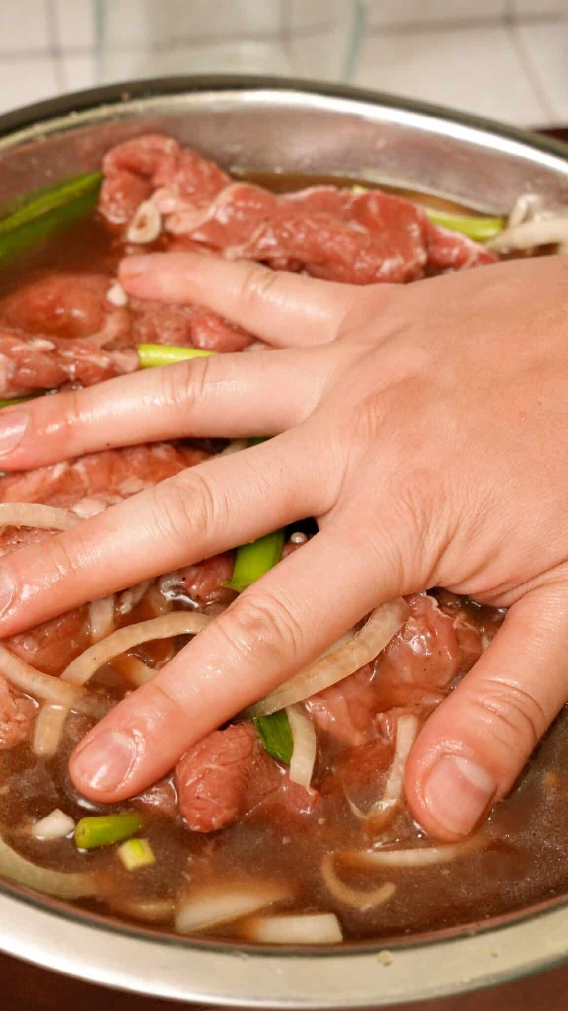 Adding steak to the bulgogi marinade in a bowl.