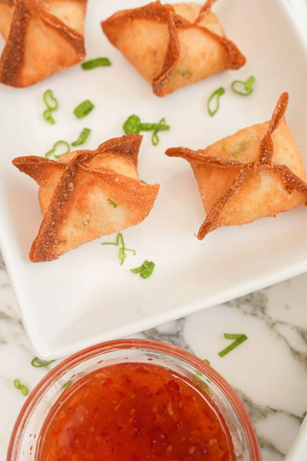 Crab rangoons on a plate with sweet thai chili sauce.