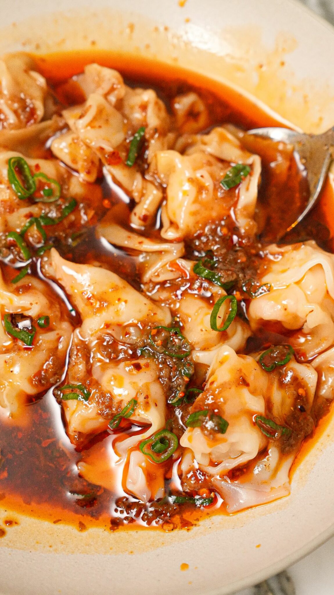 Din Tai Fung wontons in spicy sauce in a bowl.