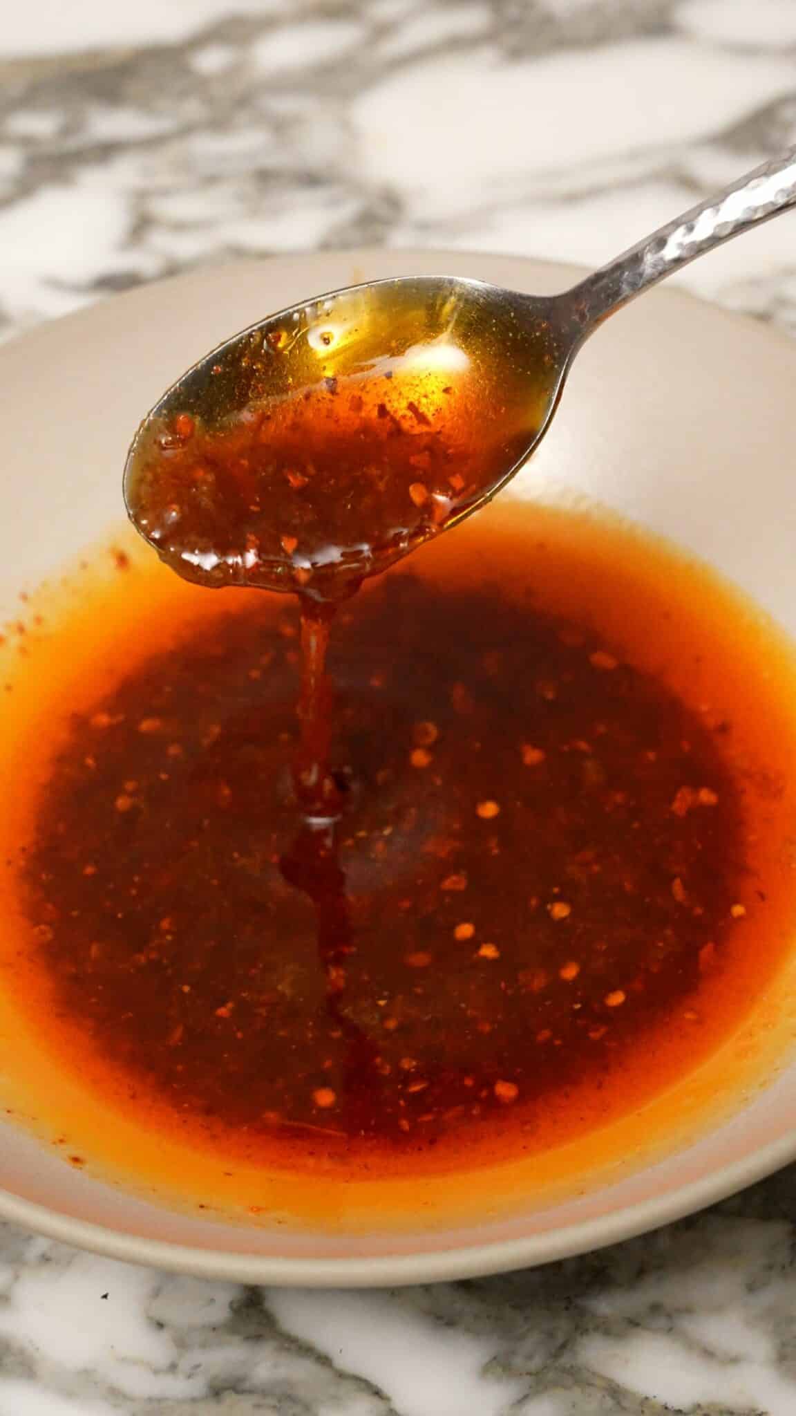 A spoon mixing the Din Tai Fung Spicy Wonton sauce.