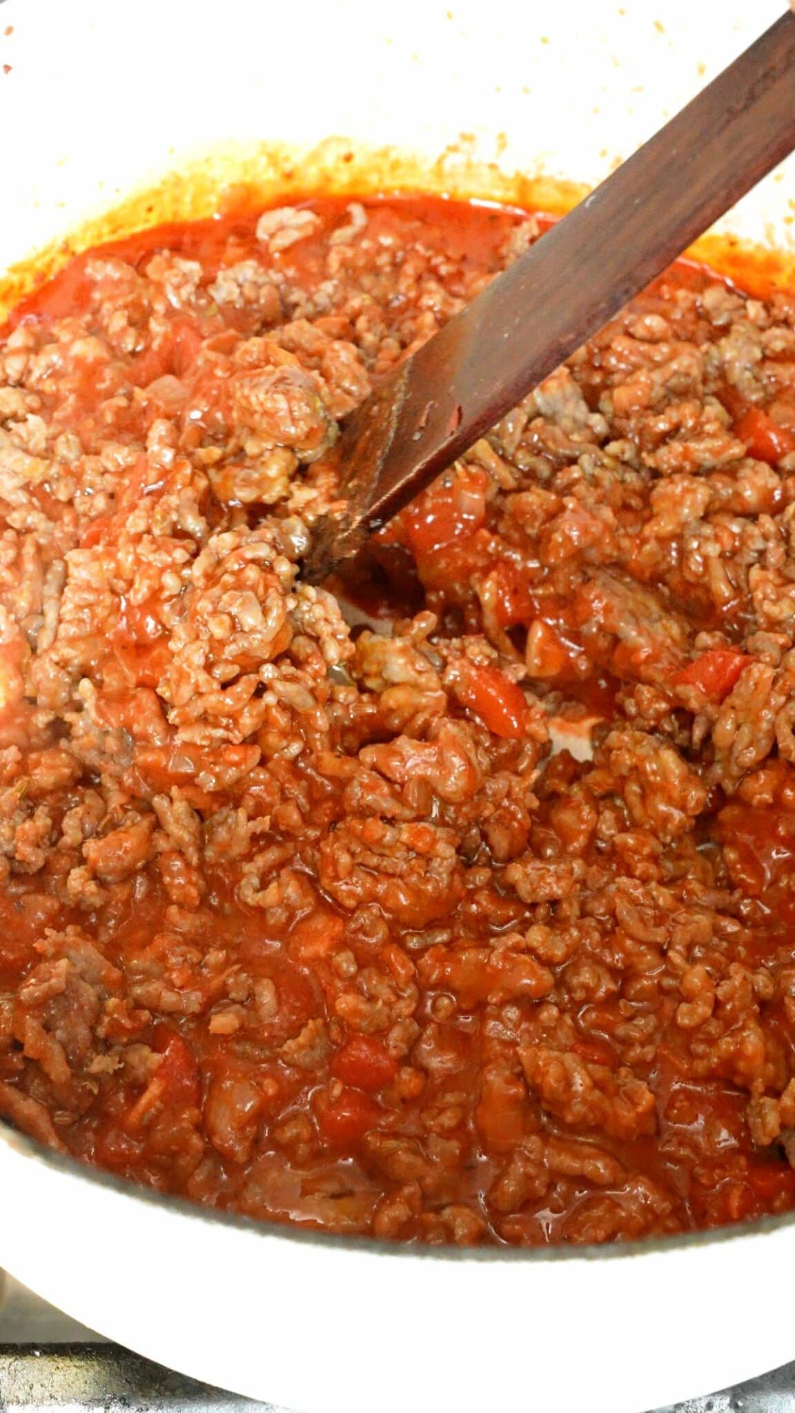 Sausage mixing with gochujang baked ziti sauce in a pot.