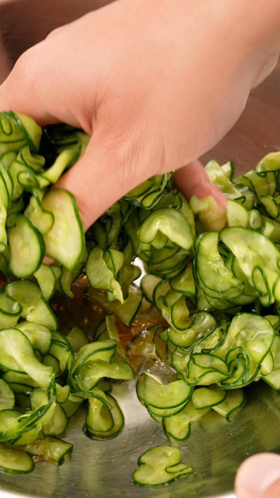 Mixing Japanese Cucumber Salad in a bowl with the dressing.