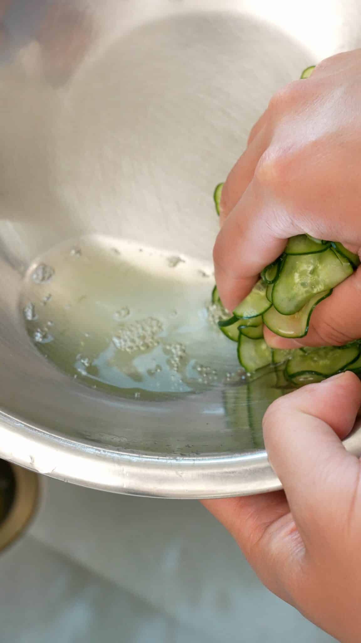 Squeezing water out of rinsed cucumbers.