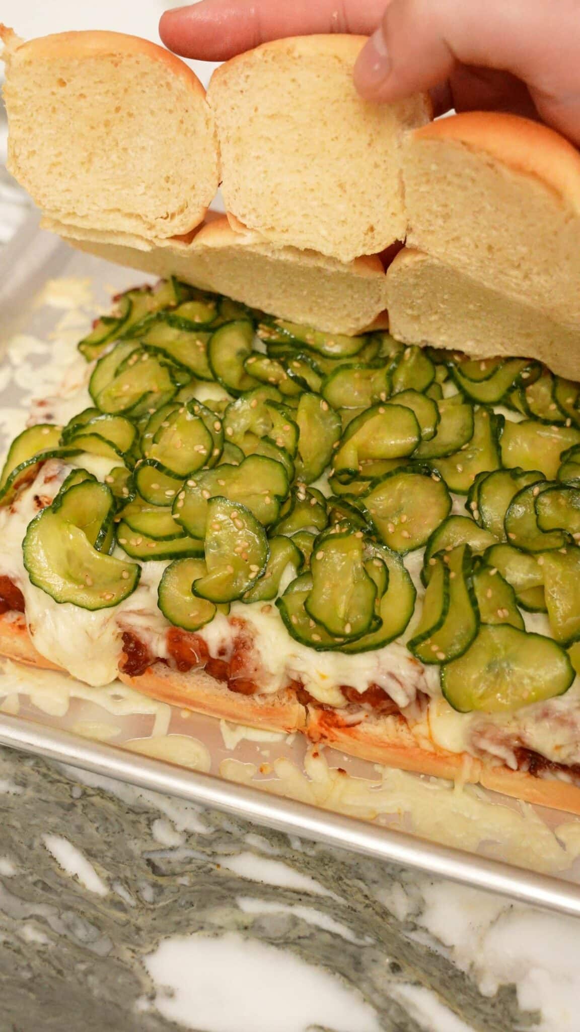 Assembling Korean Fire Chicken sliders on a tray.