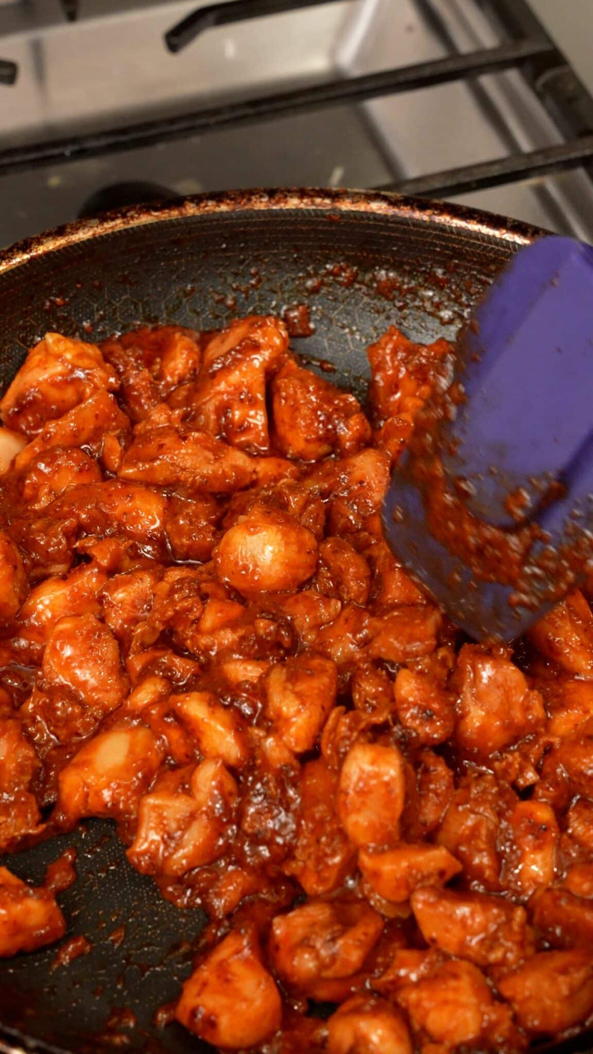 Cooking chicken in a pan for Korean fire chicken sliders.