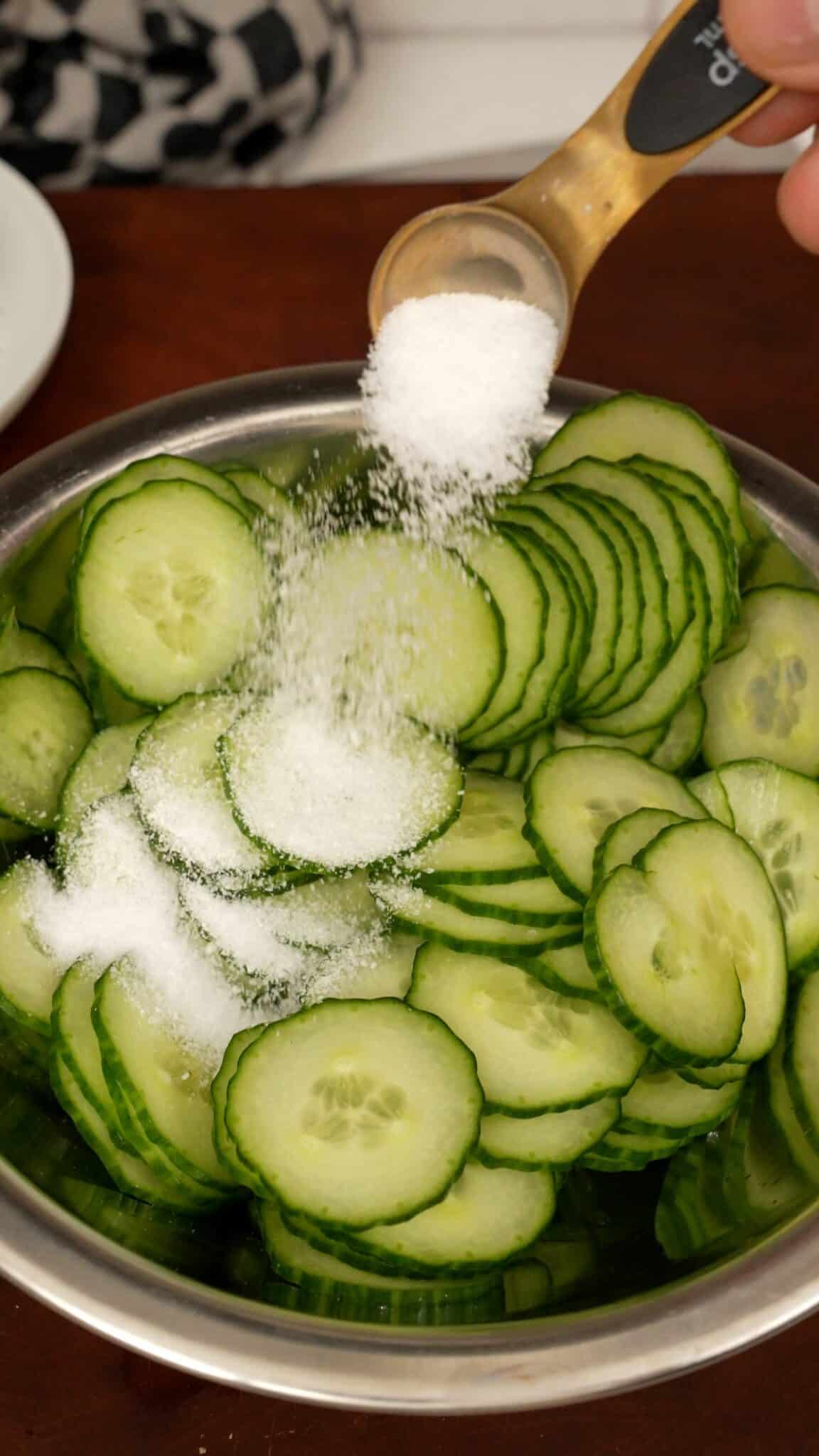 Salting cucumbers in a bowl.