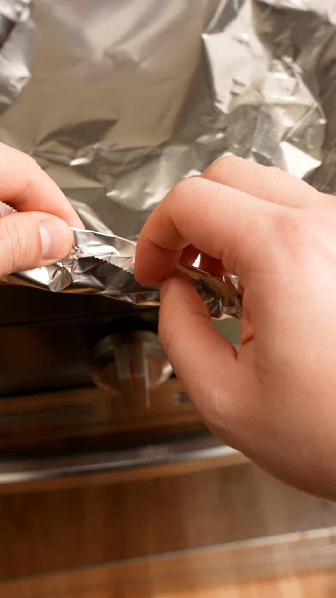 Crimping the foil to seal the ribs before baking.