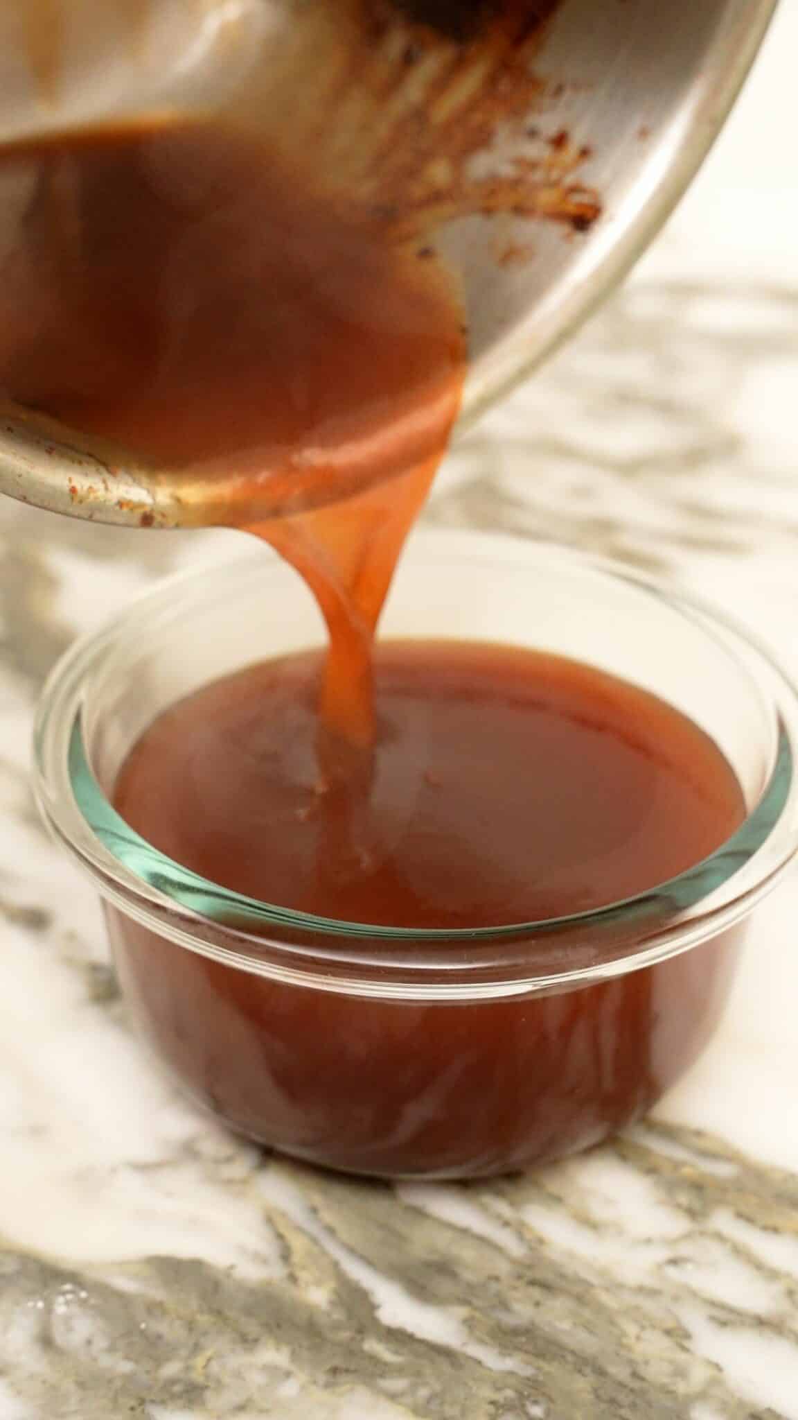 Sweet and sour sauce being poured into a glass bowl to cool.