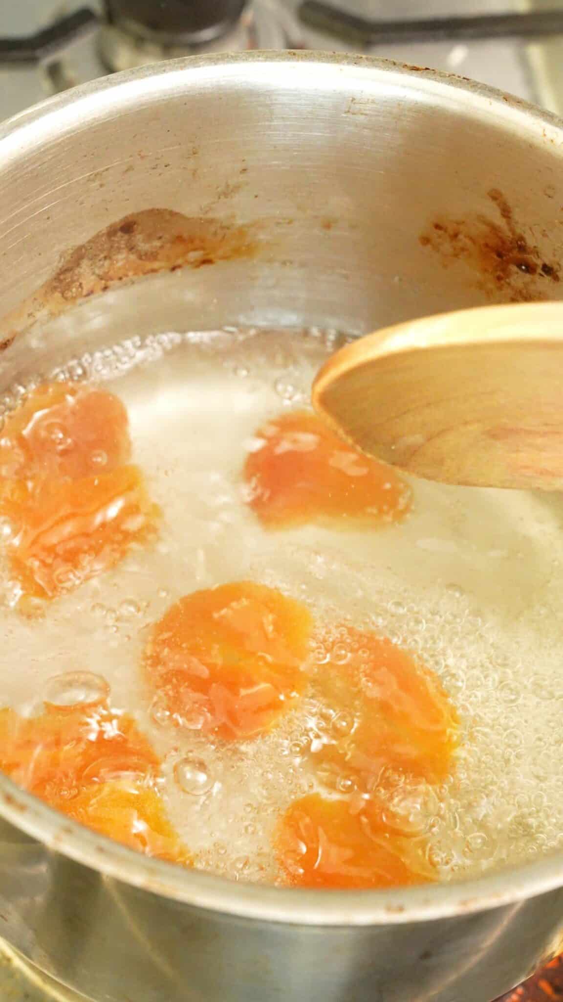 Dried apricots, sugar, and white vinegar simmering in a pot.