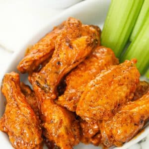 A plate of air fryer buffalo wings with celery and ranch dressings.