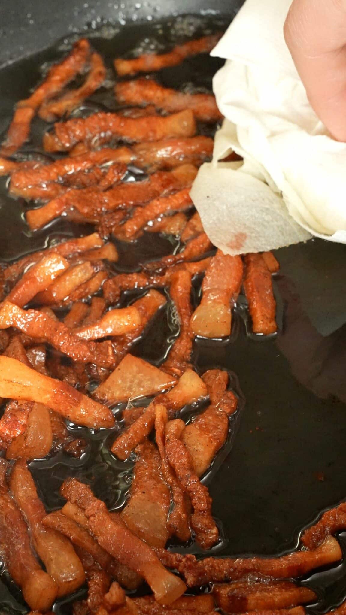 A paper towel draining guanciale fat in a pan.