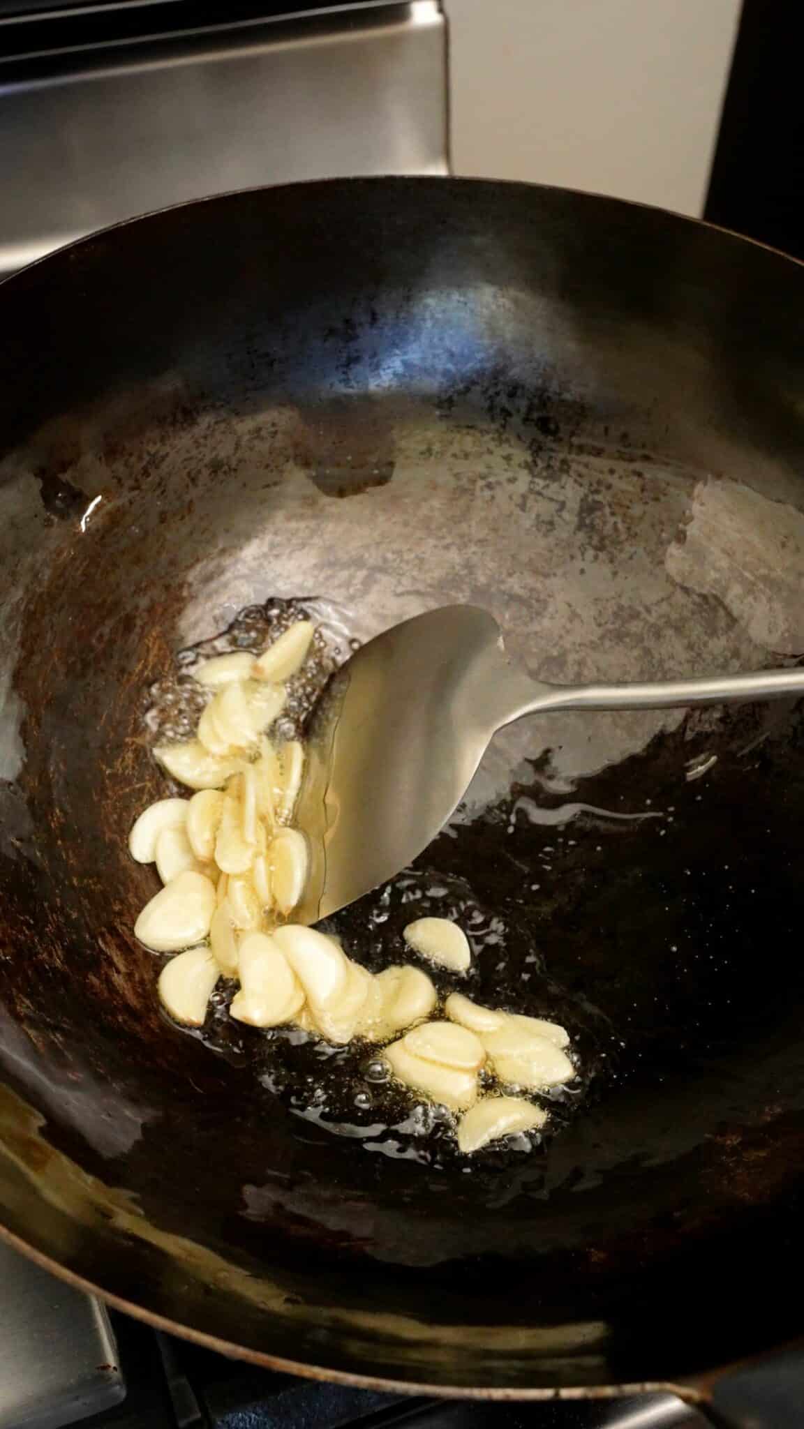 Thinly sliced garlic frying in oil in a wok.