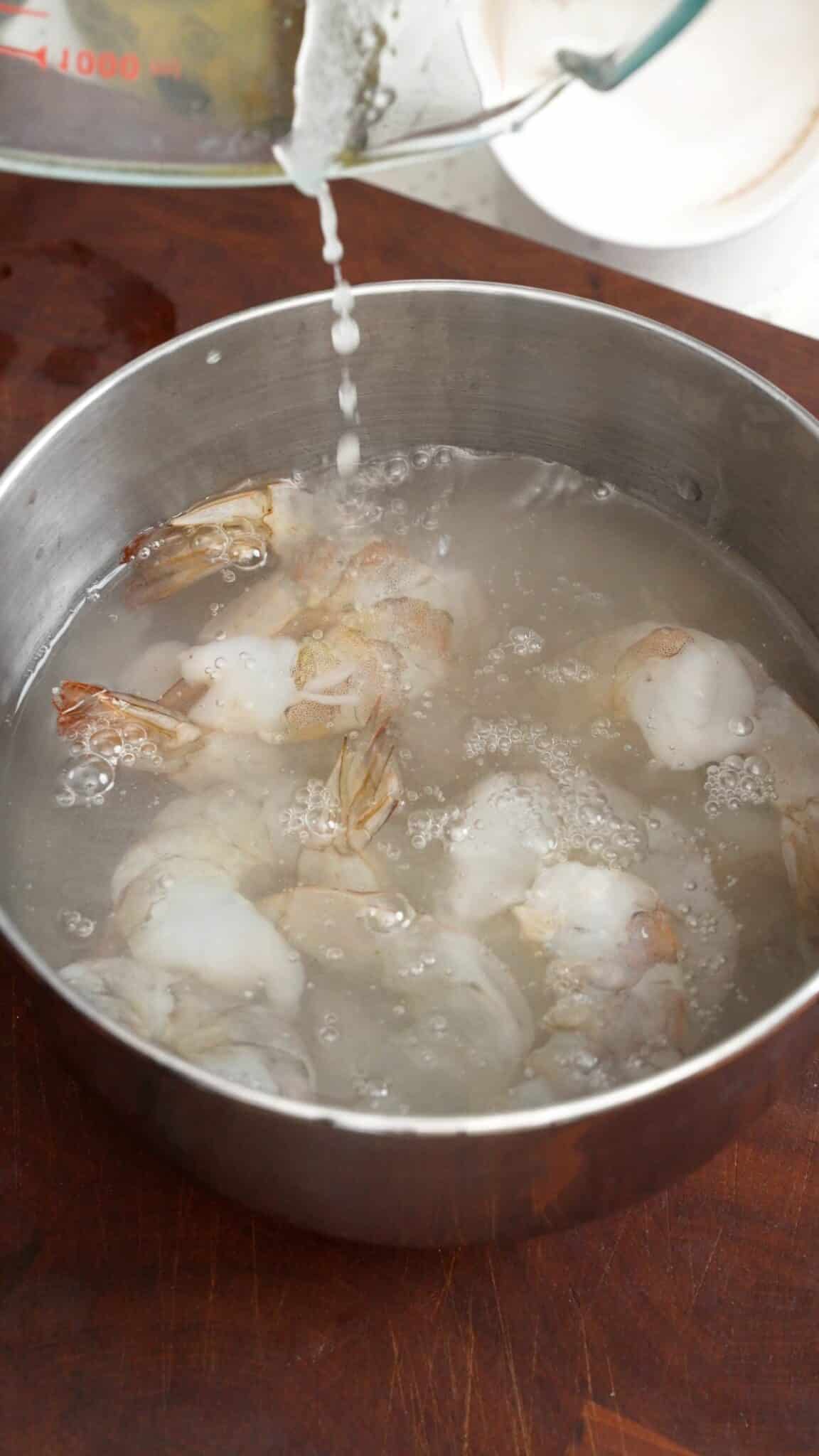 Shrimp brining in a solution of salt, sugar, and baking soda in a bowl.