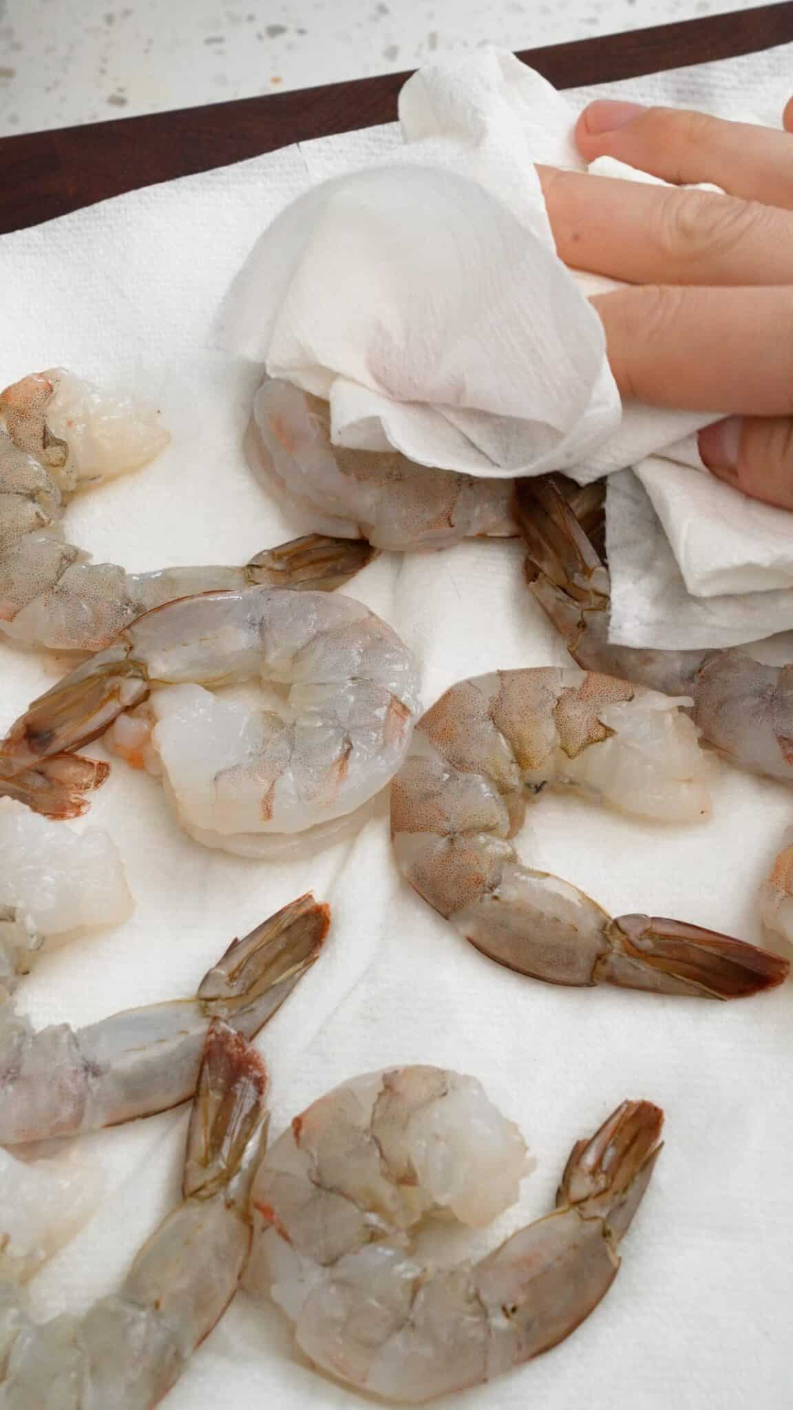 Patting shrimp dry with a paper towel.