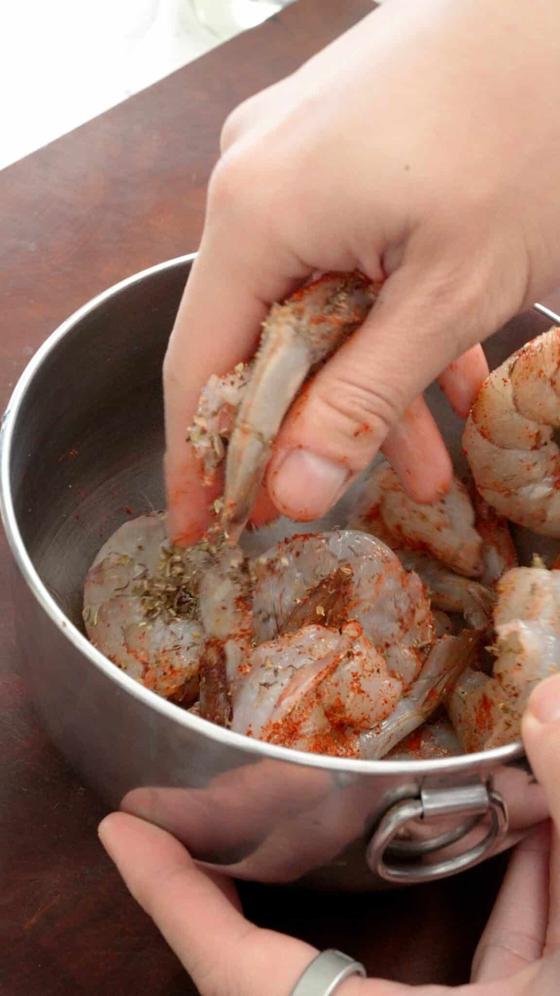 Mixing shrimp with seasonings in a bowl.
