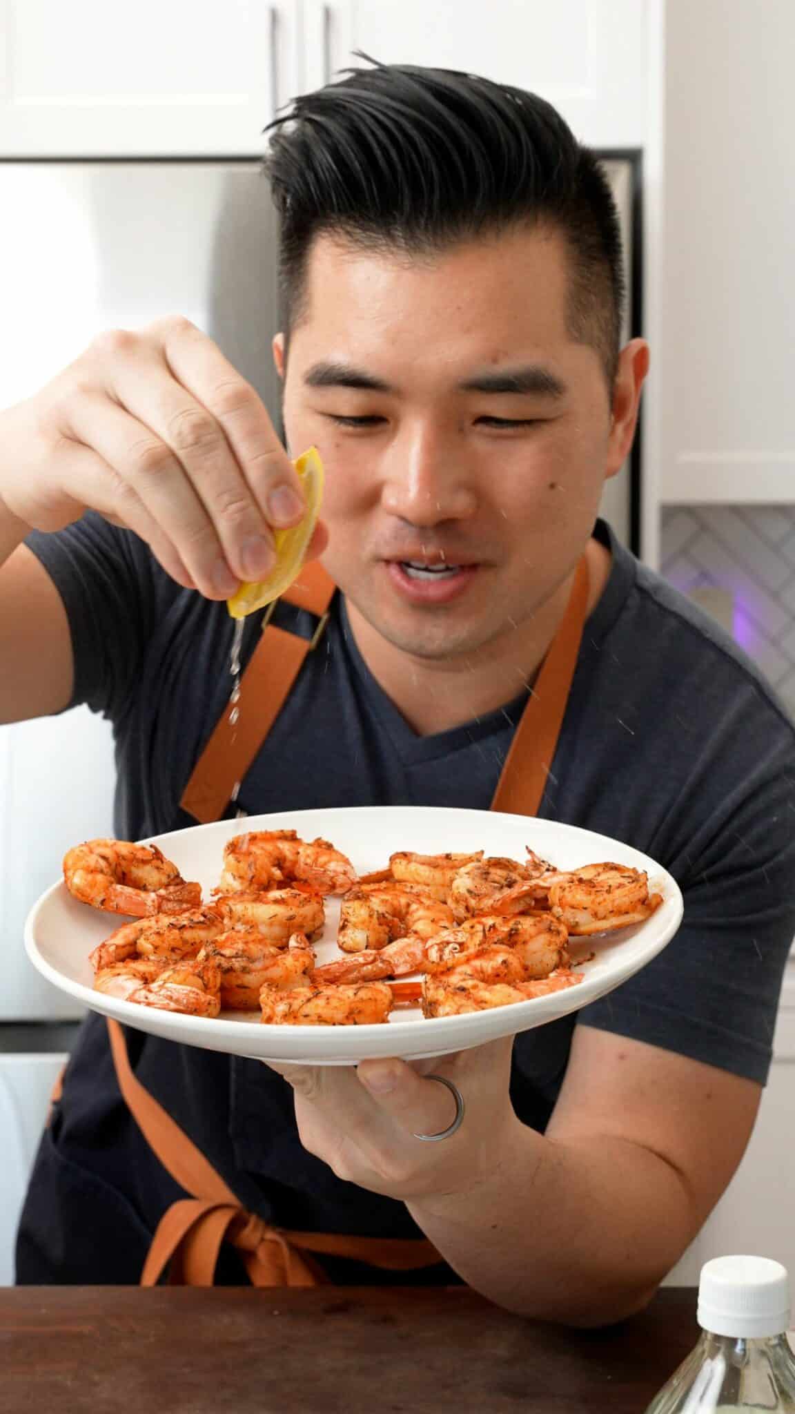 Chris squeezing fresh lemon onto the air fryer shrimp.