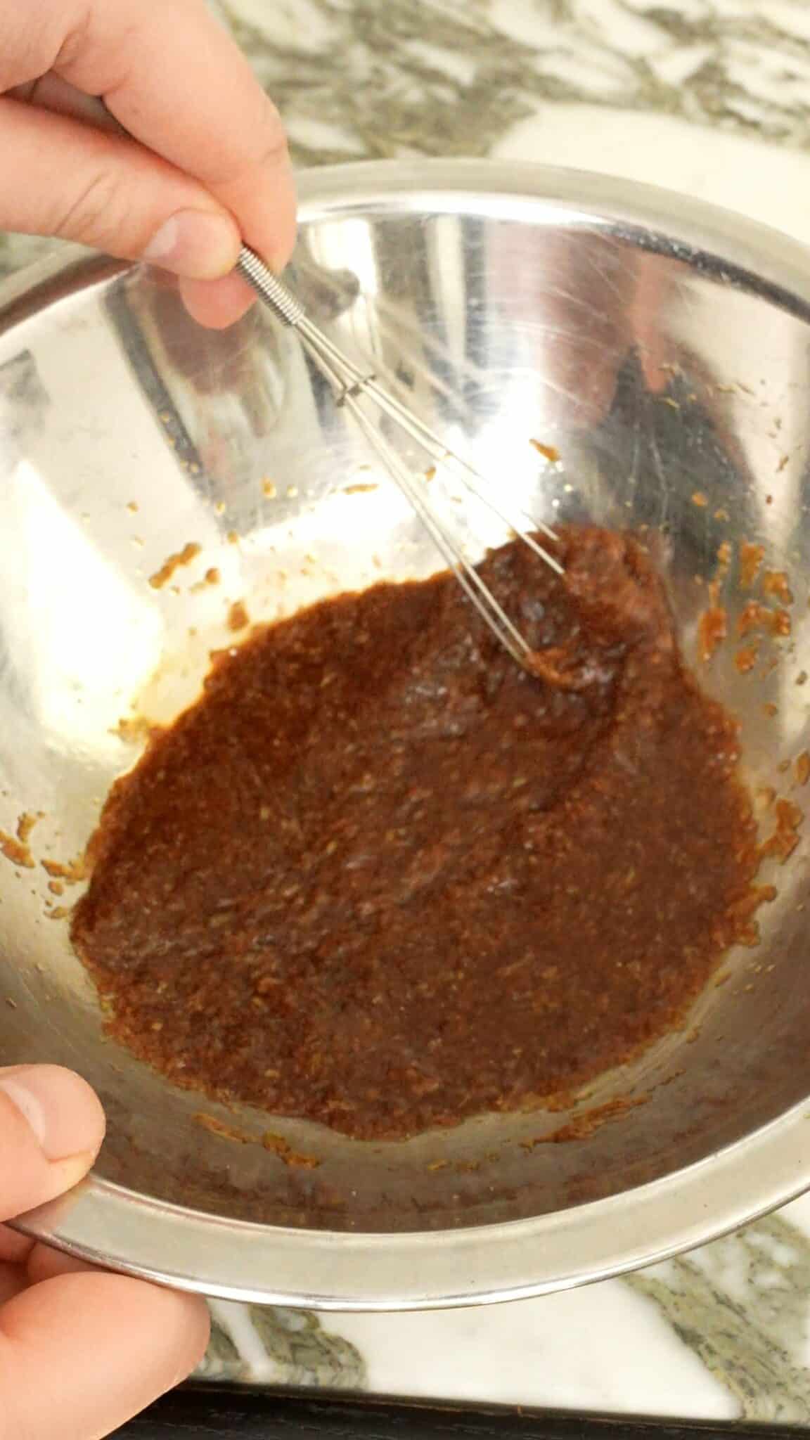 Soy sauce and grated garlic being mixed in a bowl.