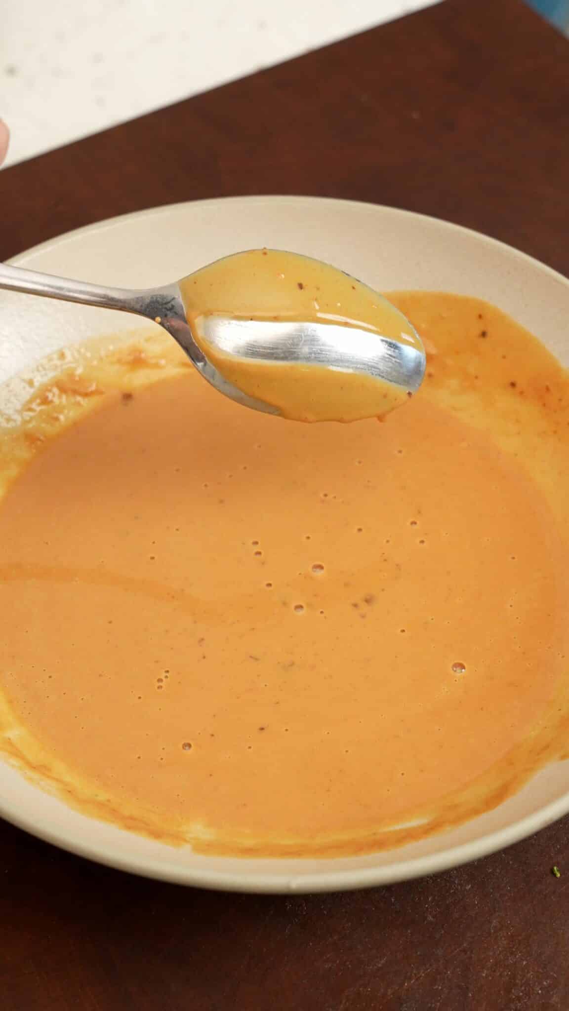 A spoon showing the consistency of the sesame sauce. The sauce is not running off the spoon.