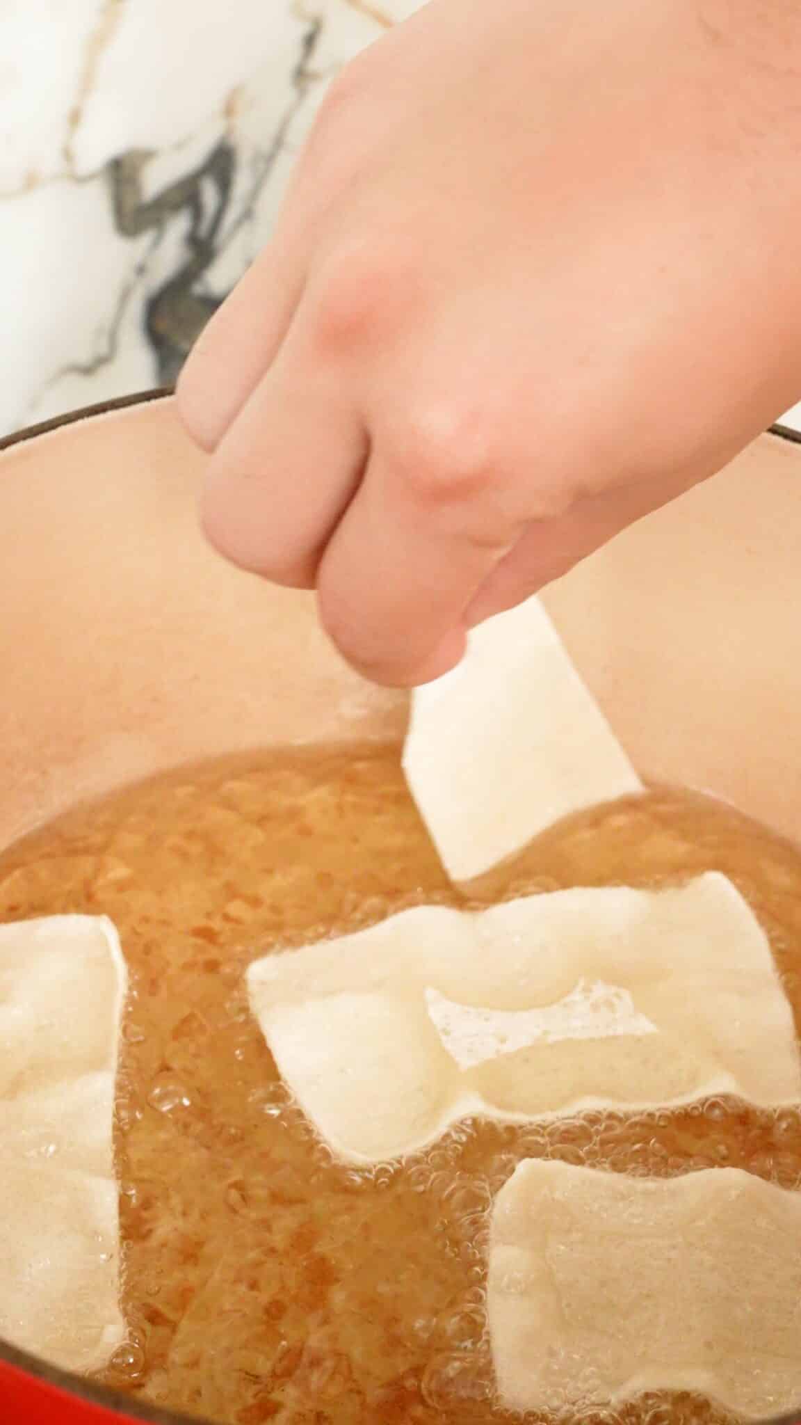 Wonton strips being fried in oil.