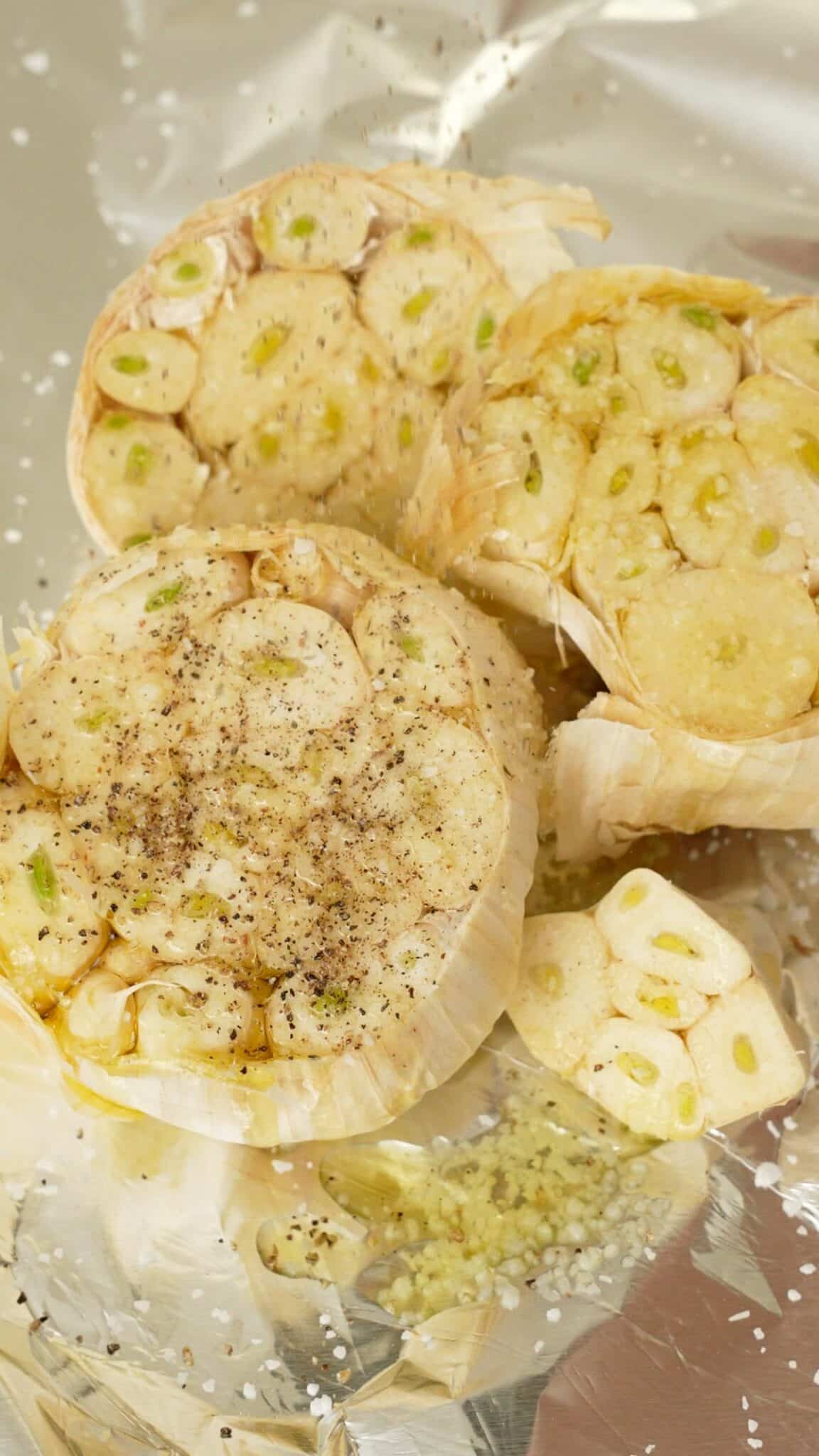 Raw heads of garlic seasoned with salt, pepper, and avocado oil.
