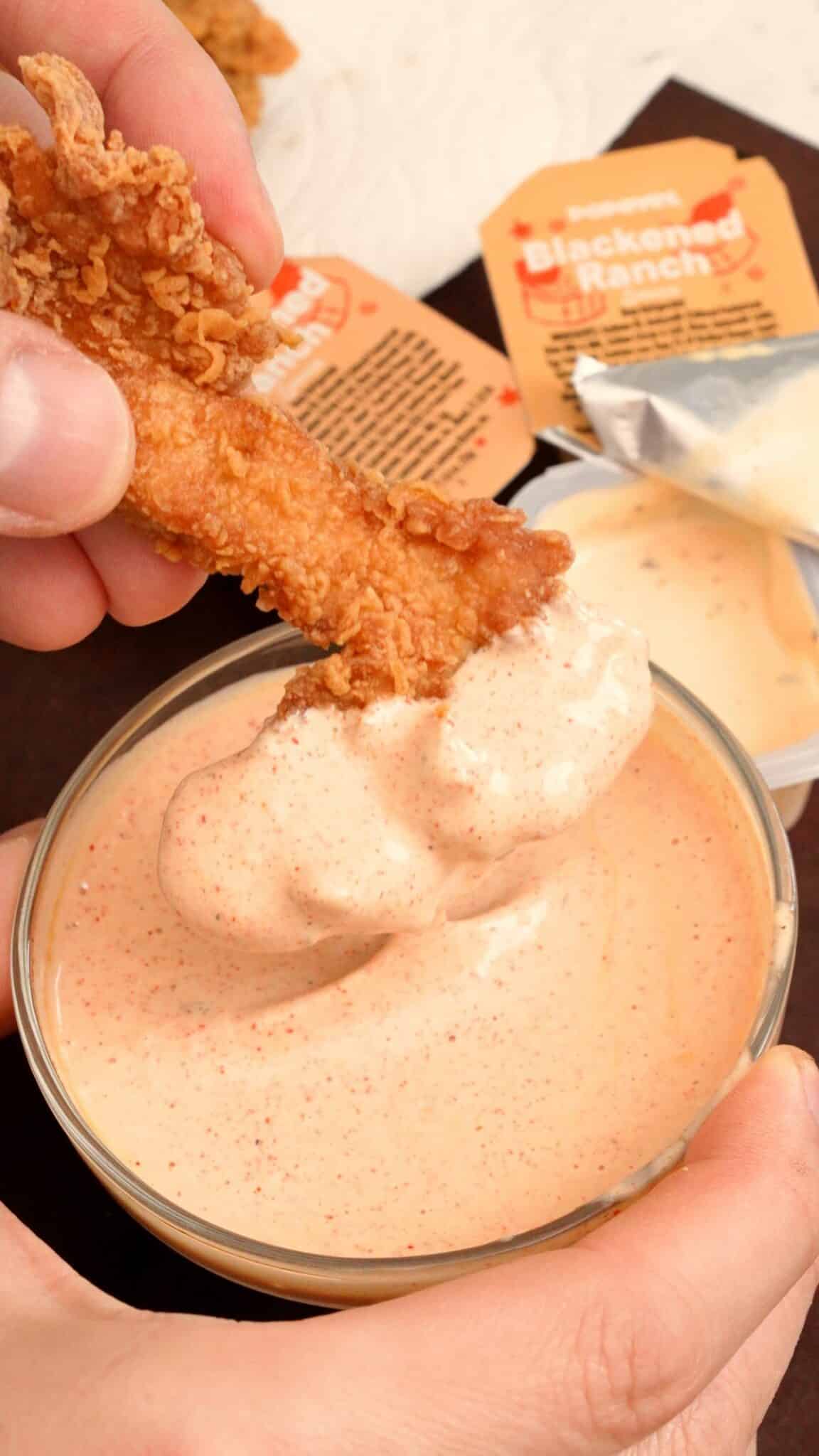 Popeyes blackened ranch with chicken fingers being dipped in it.