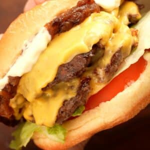 Smash Burger constructed with tomato, lettuce, beef patties, american cheese, carmelized onions, and mayo on a brioche bun.