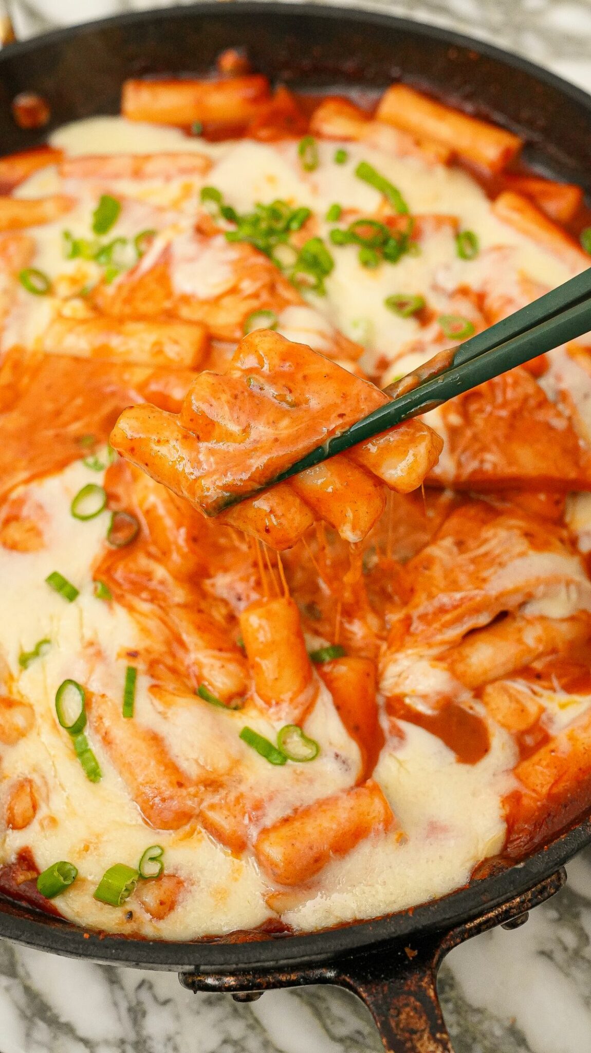 Tteokbokki in a pan with mozarella cheese.