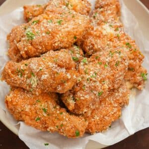 Garlic Parmesan Wings in a bowl topped with parmesan cheese and parsley.