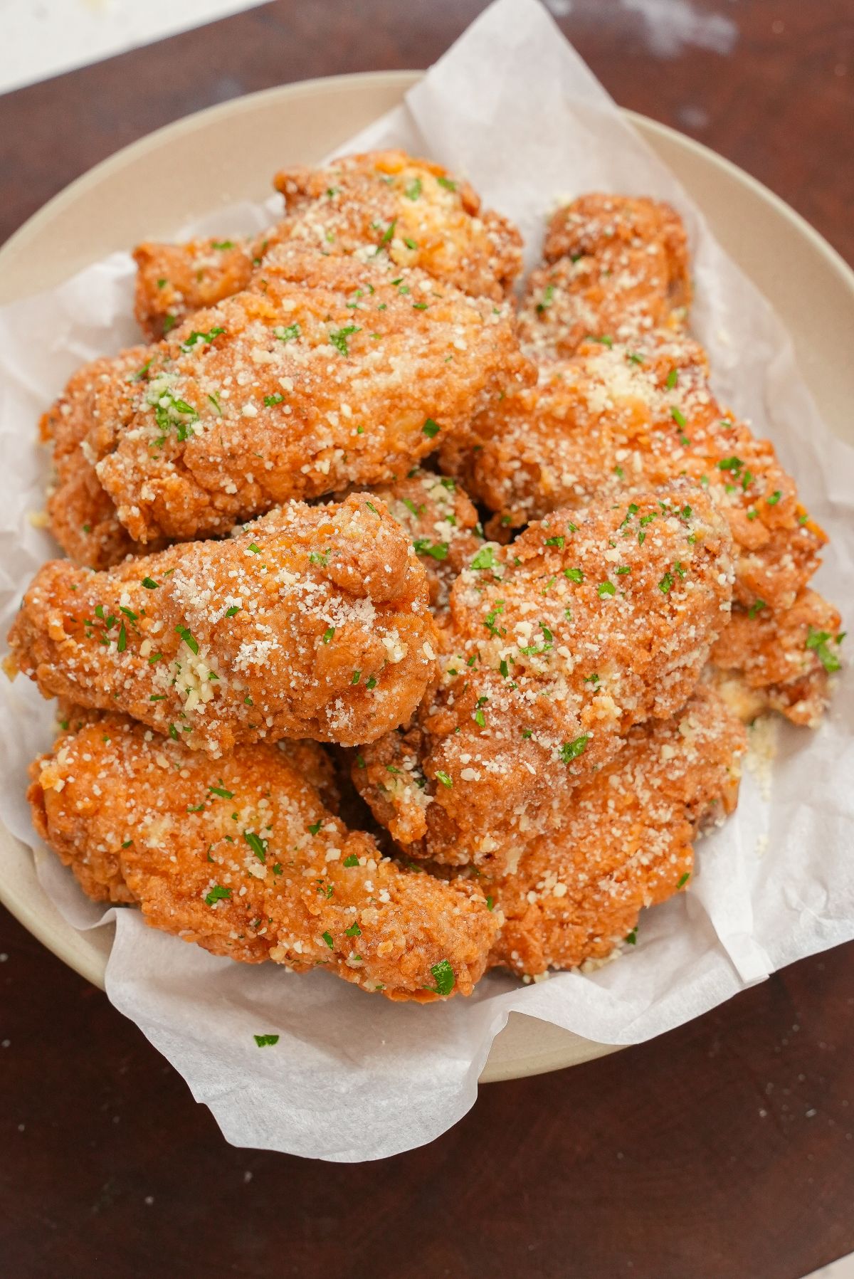 Garlic Parmesan Wings in a bowl topped with parmesan cheese and parsley.