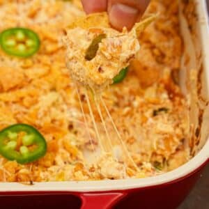Jalapeno Popper Dip being scooped with a tortilla chip.