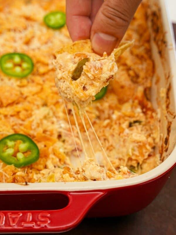 Jalapeno Popper Dip being scooped with a tortilla chip.