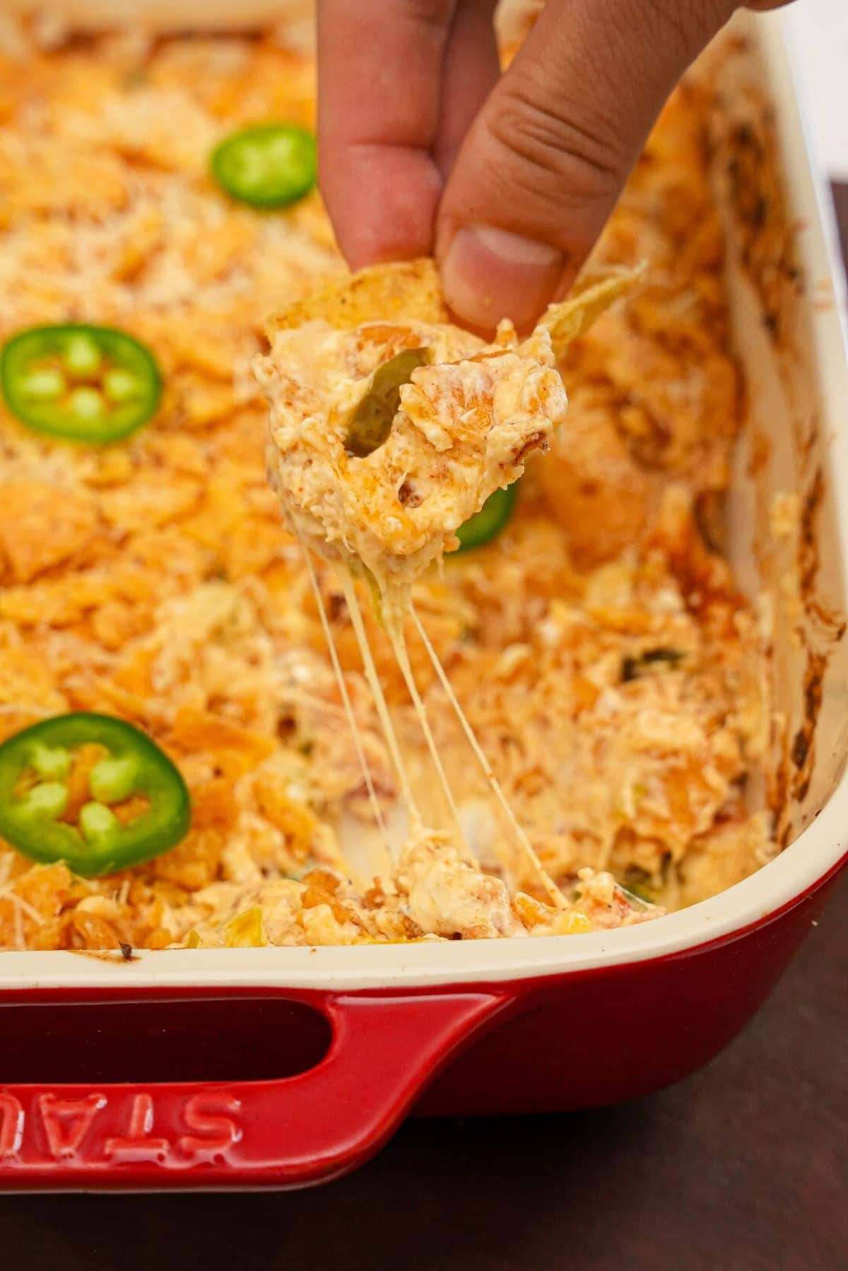 Jalapeno Popper Dip being scooped with a tortilla chip.
